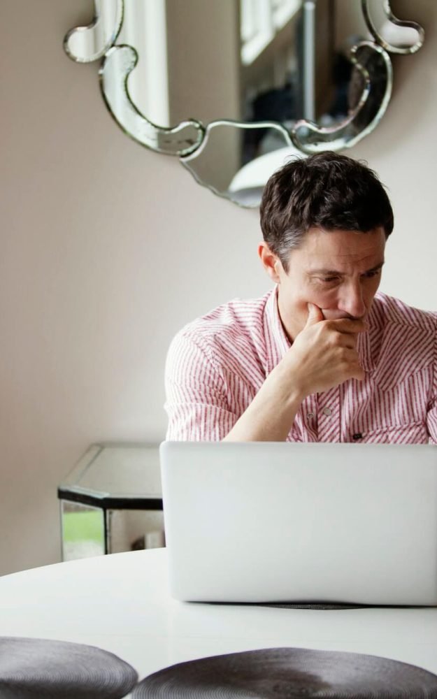 man-looking-at-credit-card-while-siting-by-table-1.jpg